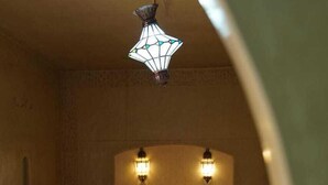 A bedroom with two beds, a patterned floor, and a hanging light fixture. - Dar Lkhalifa Merzouga (Taouz)
