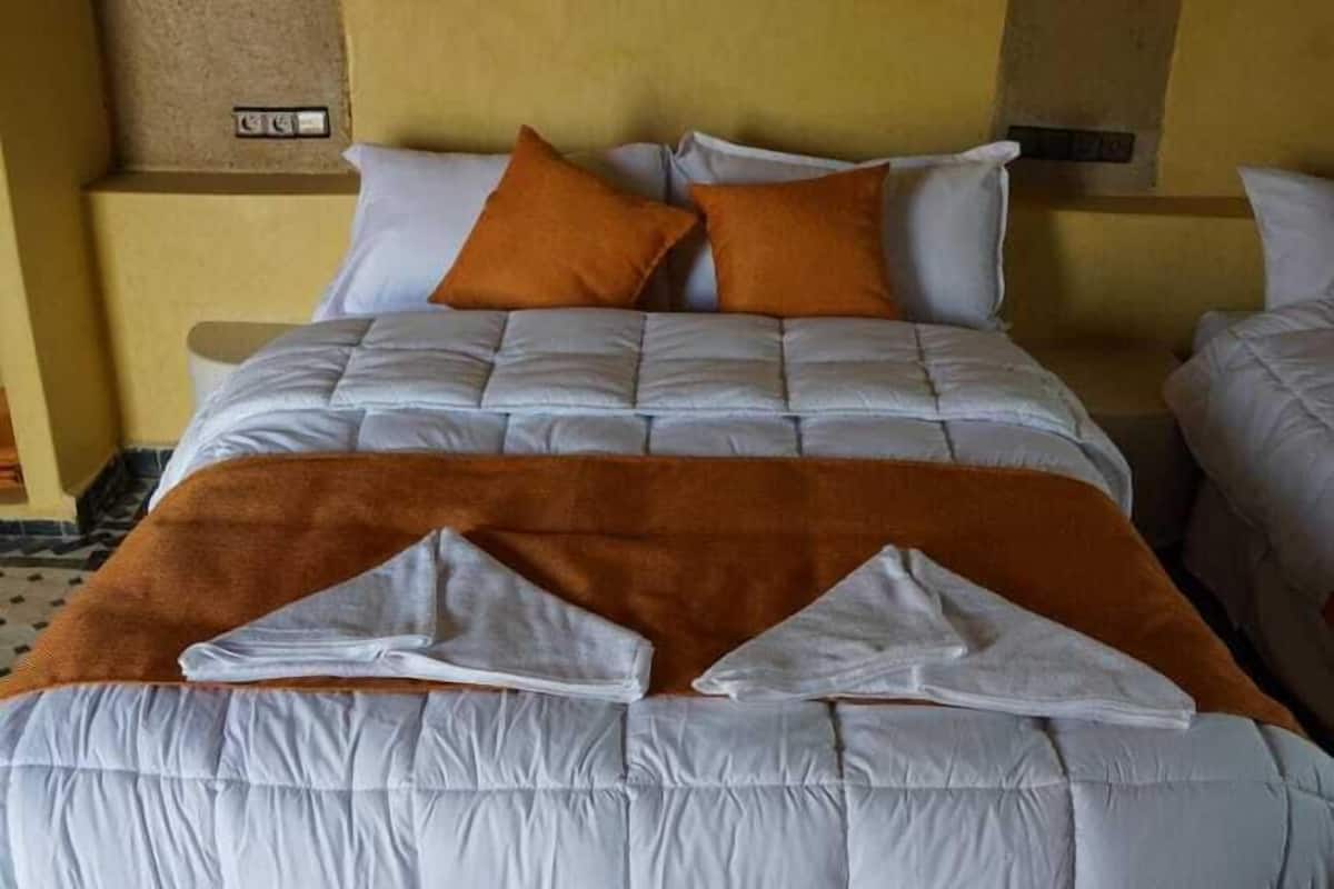 Un lit avec une tête de lit, des oreillers et une couverture.