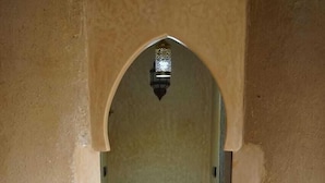 A bathroom with a sink under an archway, tiled floor, and a hanging light fixture. - Dar Lkhalifa Merzouga (Taouz)