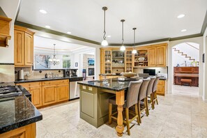 A spacious kitchen with a central island, wooden cabinets, and pendant lighting.