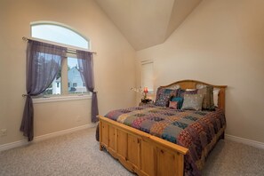 Un dormitorio con una cama de madera, una ventana con cortinas y una mesita de noche con lámpara.