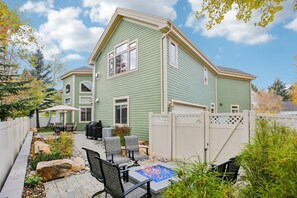 A two-story house with a patio area featuring outdoor furniture and a fire pit.