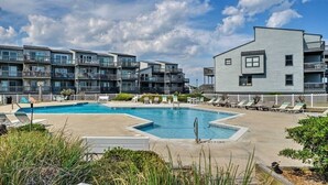 A modern building with multiple balconies and a swimming pool area with lounge chairs. - Oceanfront Escape - Private Beach Access – Pool – Spacious Balcony – Sleeps 6 (North Topsail Beach)