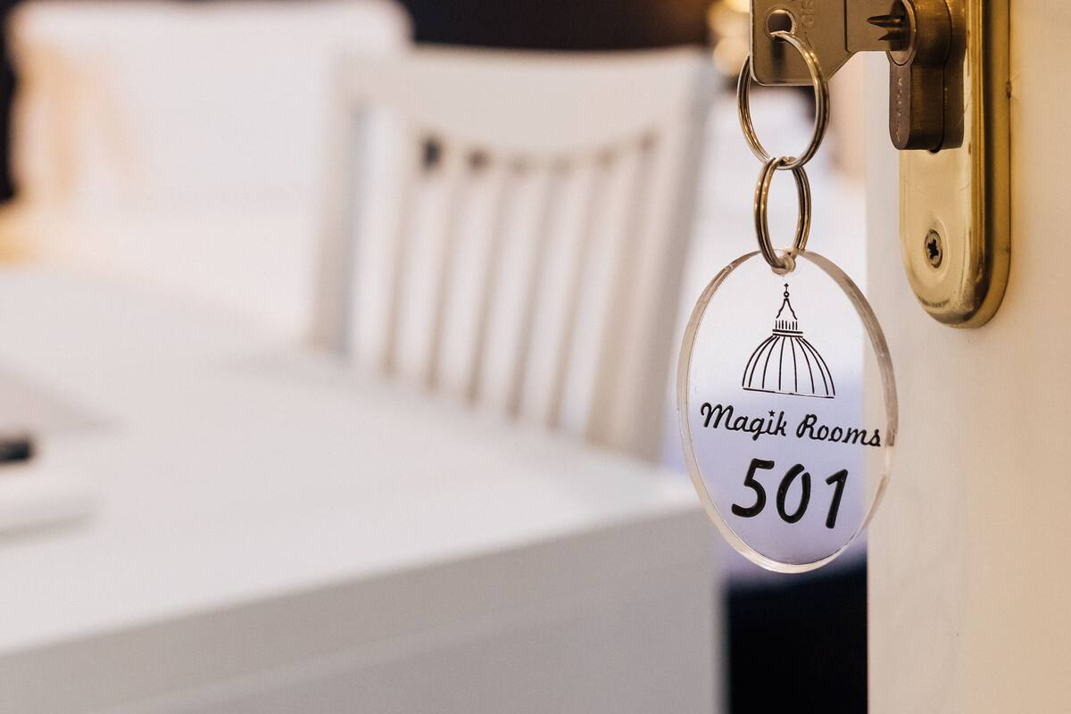 Puerta de una habitación de hotel con un llavero que dice "Magik Rooms 501" y un cuadro en la pared.