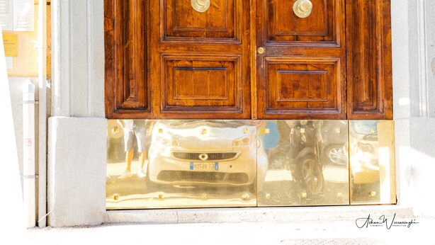 A large wooden double door with a brass handle, set within an arched stone frame. - Magik Rooms (Rome)