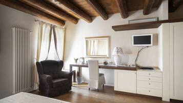 A bedroom with a wooden ceiling, a bed, a desk with a chair, a television, and a radiator.
