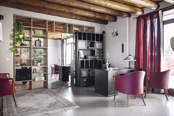 A spacious living area with a wooden ceiling, a large open shelving unit, and a desk with chairs. - Corte dei Soavi (Soave)