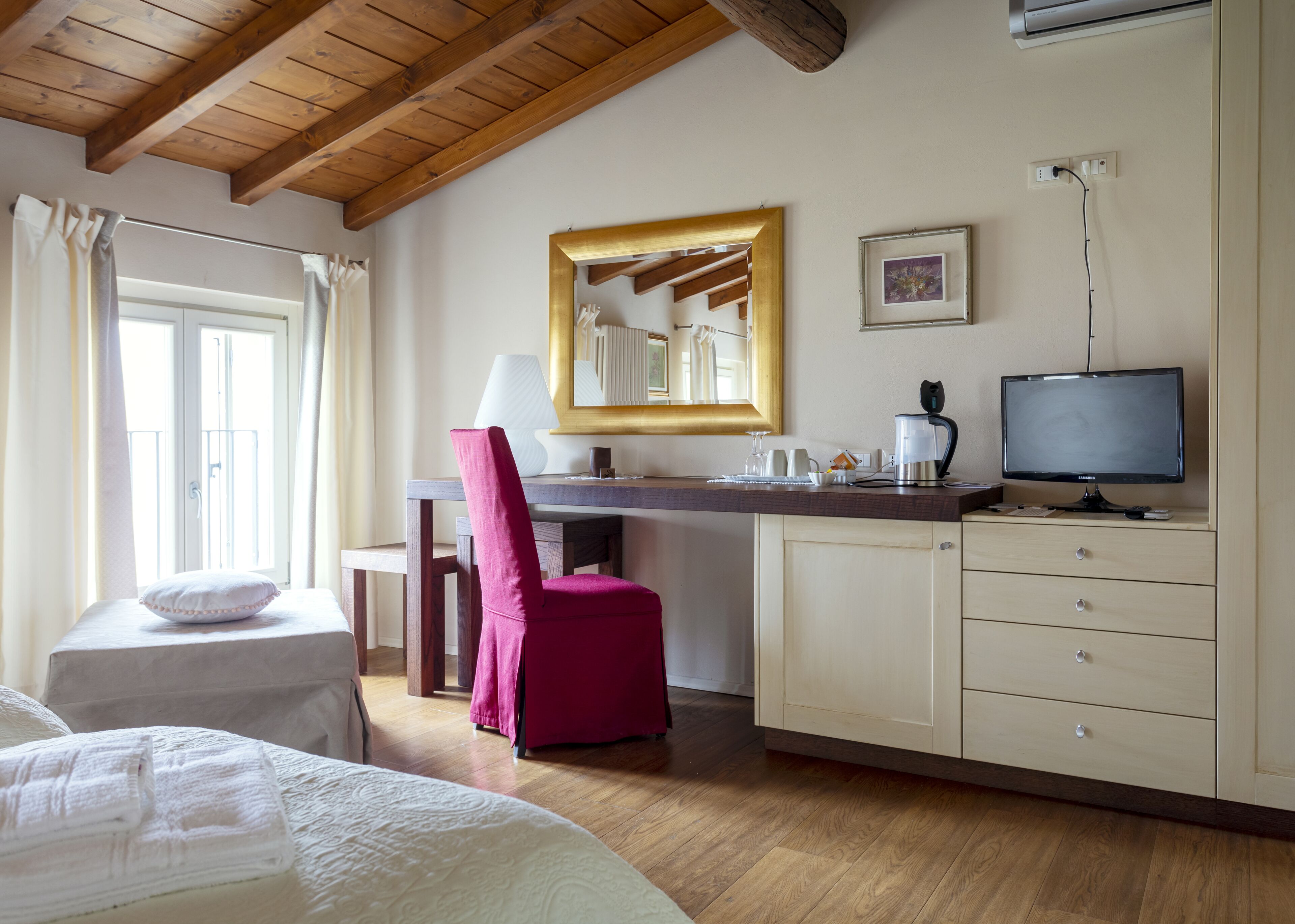 A hotel room with a bed, a desk with a chair, a television, and a mirror.