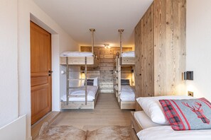 Une pièce avec des lits superposés, des murs en bois, une porte en bois et un luminaire.