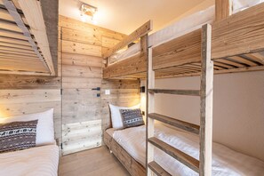 Une pièce de style cabane en bois, avec des lits superposés et un plafond en pente.