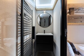 Une petite salle de bain avec un miroir rond, un lavabo et une douche.