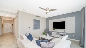 Ein modernes Wohnzimmer mit einem weißen Sofa, einem Couchtisch und einem an der Wand befestigten Flachbildfernseher.