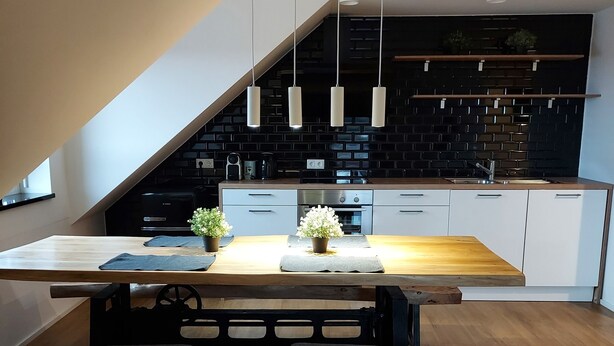Una cocina moderna con una mesa de comedor de madera, bancos y luminarias colgantes.