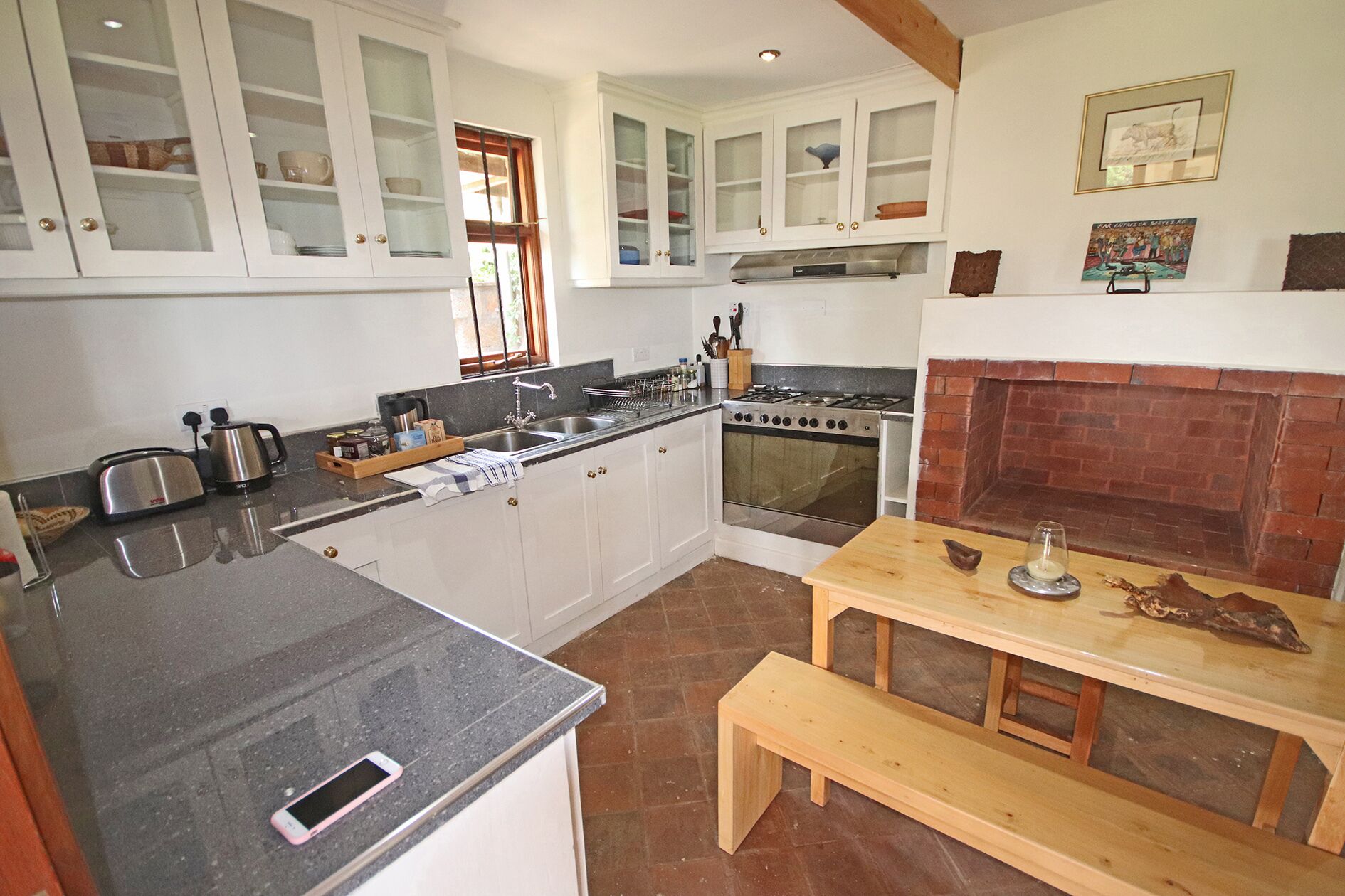 A kitchen with white cabinets, a stove, and a brick fireplace.