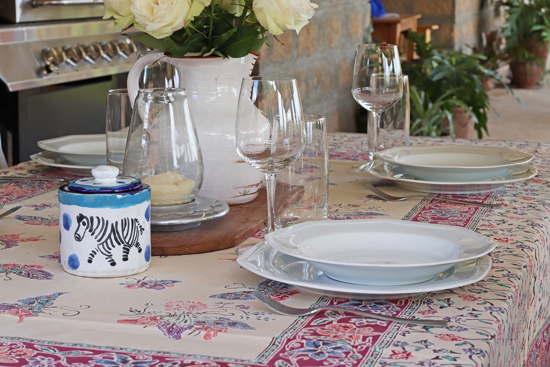 Ett bord dukat med tallrikar, glas, en kanna och en dekorativ vas med blommor.