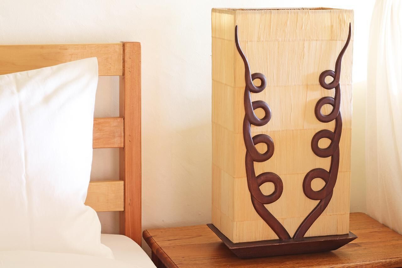 Un lit avec une tête de lit en bois et une table de chevet surmontée d’une lampe décorative en bois.
