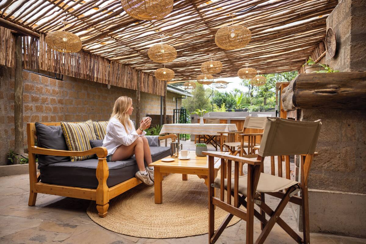 Un espacio al aire libre con sofá, sillas, una mesa y techo de mimbre.