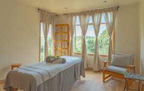 A room with a bed, a chair, a small table, and large windows with curtains. - Olesamara Collection (Nanyuki)