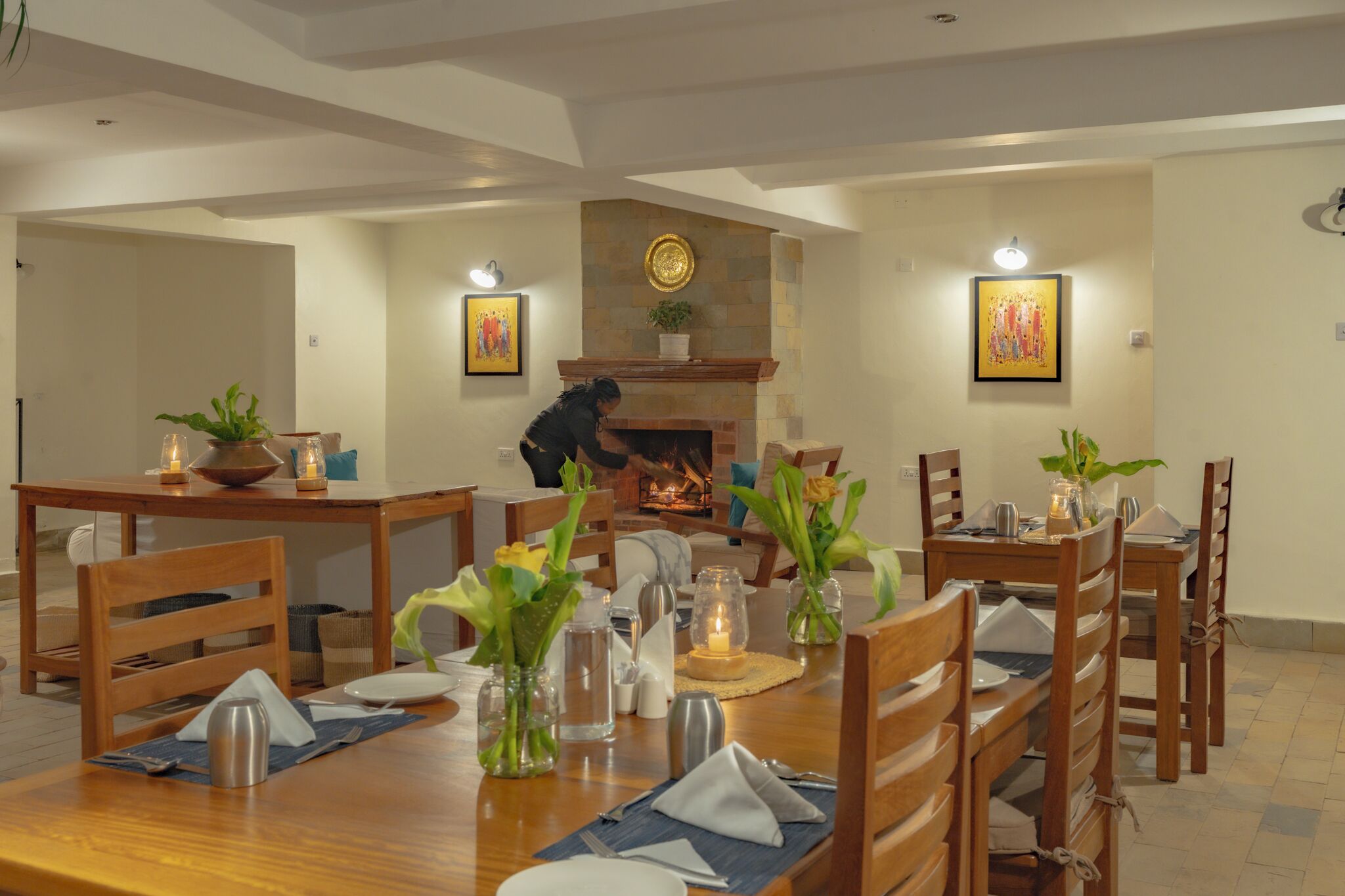 A dining area with a fireplace, wooden furniture, and artwork on the walls.