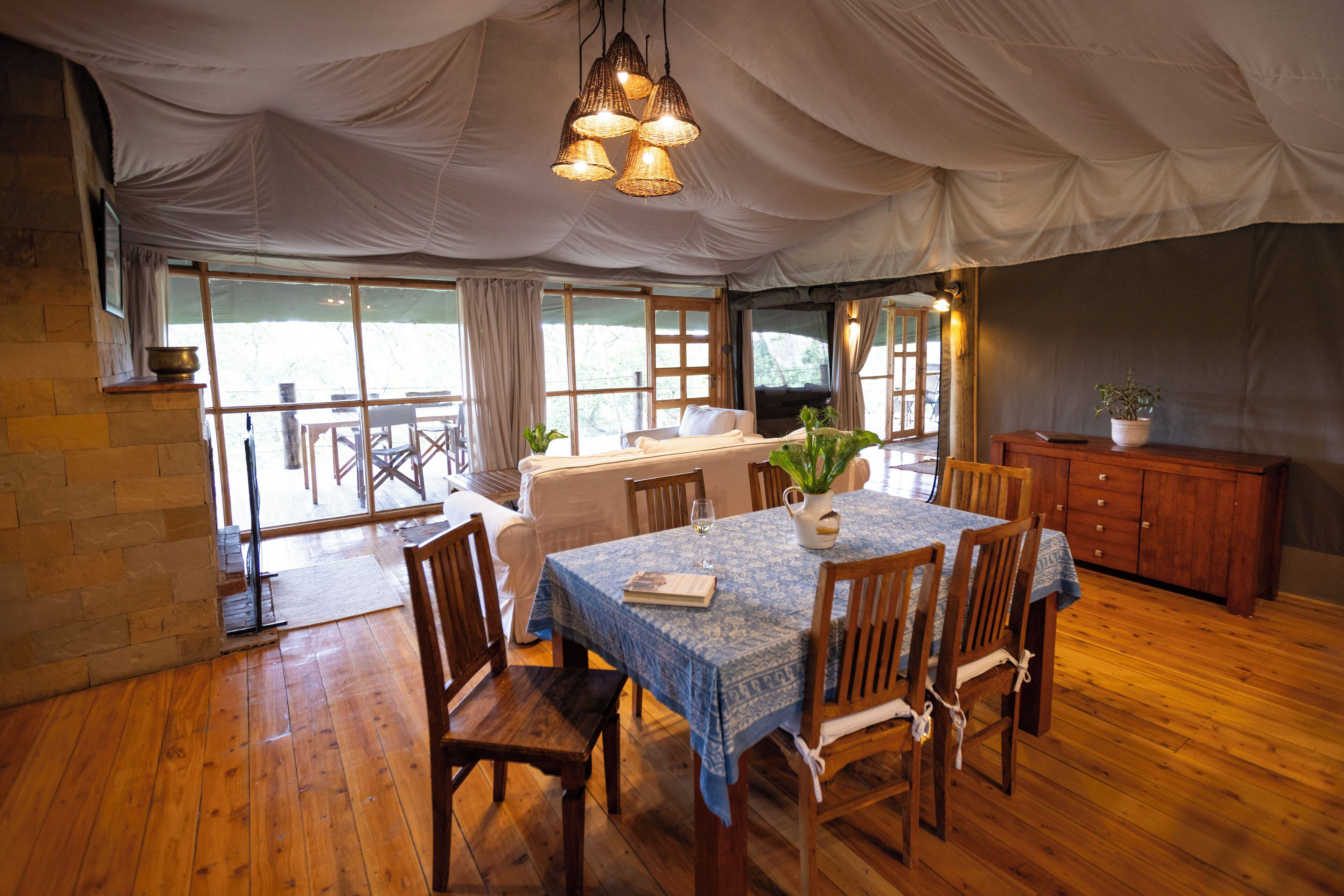 A tented dining area with a wooden table, chairs, and a chandelier.