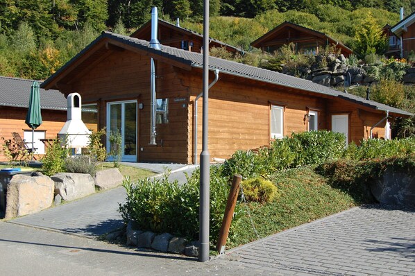 A wooden cabin with a chimney, a door, and a window.