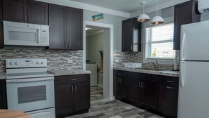 Uma cozinha moderna com armários de madeira escura, geladeira branca, micro-ondas embutido, forno duplo e backsplash revestido de azulejos.