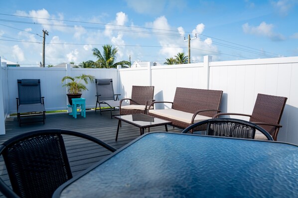 An outdoor patio area with wicker furniture, a small table, and a potted plant.