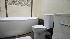 A bathroom with a bathtub, toilet, and a cabinet. - Comfy & brand new downtown apartment (Chisinau)