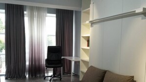 A modern living room with a sofa, a chair, a small table, and a bookshelf. - Comfy & brand new downtown apartment (Chisinau)