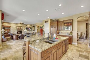 A spacious kitchen with granite countertops, wooden cabinets, and a stone backsplash.