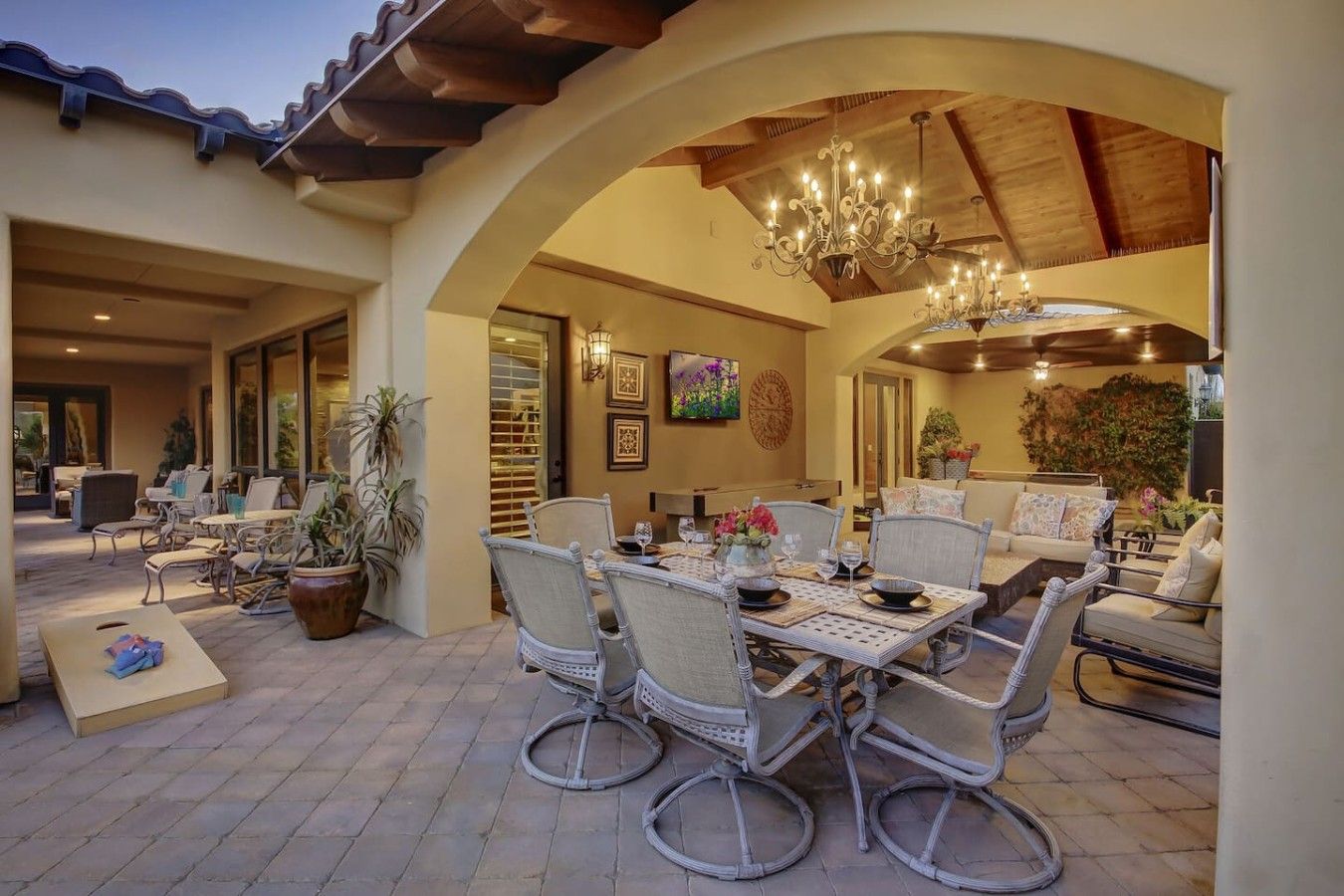 Pátio externo com mesa de jantar para quatro pessoas, rodeado por cadeiras de vime.