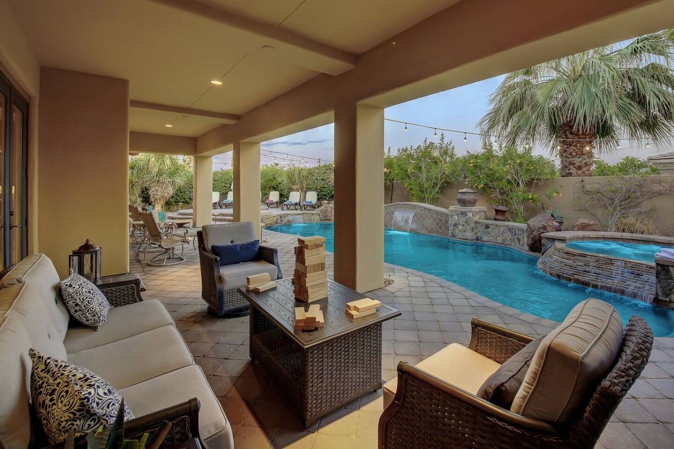 Ein Terrassenbereich im Freien mit Pool, Sitzgelegenheiten und einem Wasserfall.