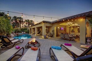 A poolside area with lounge chairs, a fire pit, and string lights. - Tuscany: Pool, Spa, Fire Pit, Ping Pong Games (Indio)