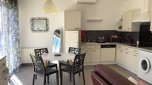 A compact kitchen with a dining table, chairs, a bench, and a washing machine. - THE QUIET HOUSE BETWEEN SEA AND MOUNTAIN (MARCORIGNAN)