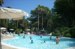 Un espace piscine équipé de chaises longues et de parasols.