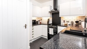 Een moderne keuken met witte kasten, een zwart aanrecht en een roestvrijstalen afzuigkap.