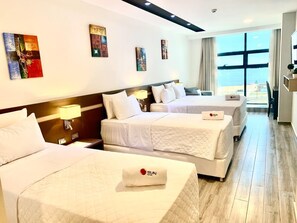 A hotel room with three beds, a large window, and artwork on the walls. - Sun Hotel (Encarnacion)