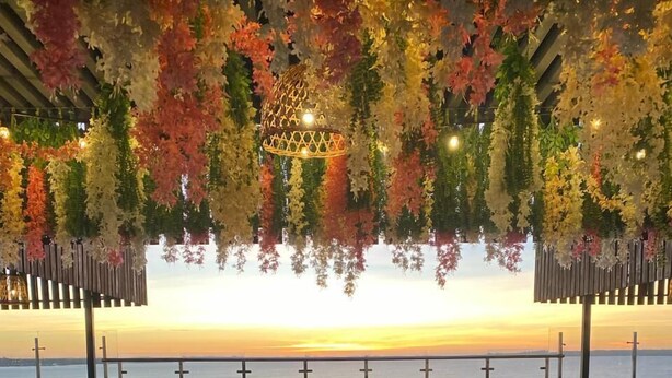 A terrace with a pool, chairs, and a view of the sunset over the water. - Sun Hotel (Encarnacion)