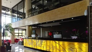 A hotel reception area with a marble counter, seating area, and large windows. - Sun Hotel (Encarnacion)