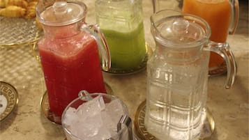 Différentes boissons servies dans des carafes en verre, ainsi qu'un verre d'eau sur un plateau.