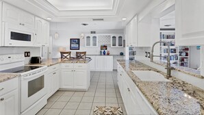 Uma cozinha moderna com armários brancos, forno embutido, micro-ondas e bancada de granito.