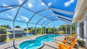 Piscina descoberta coberta com vista para uma casa e um corpo de água ao fundo.