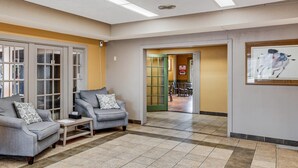 A lobby with two grey sofas, a small table, and a framed artwork on the wall. - Econo Lodge Whitehall near Michigan's Adventure (Whitehall)
