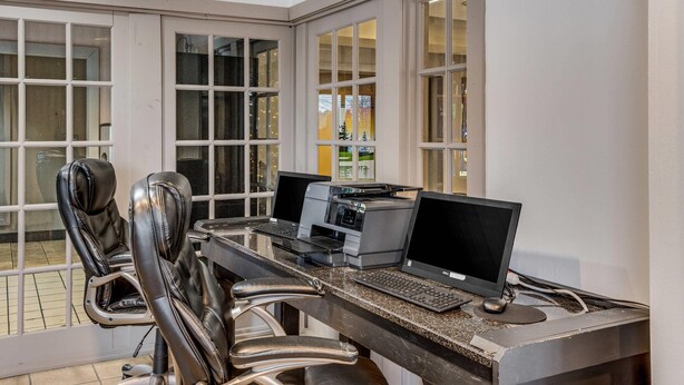 A corner office with two desks, each with a computer and printer, leather chairs, and large windows with blinds. - Econo Lodge Whitehall near Michigan's Adventure (Whitehall)