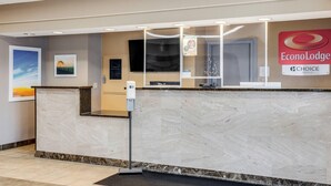 A reception area with a marble counter, a digital screen, and a sign for EconoLodge Choice Hotels. - Econo Lodge Whitehall near Michigan's Adventure (Whitehall)