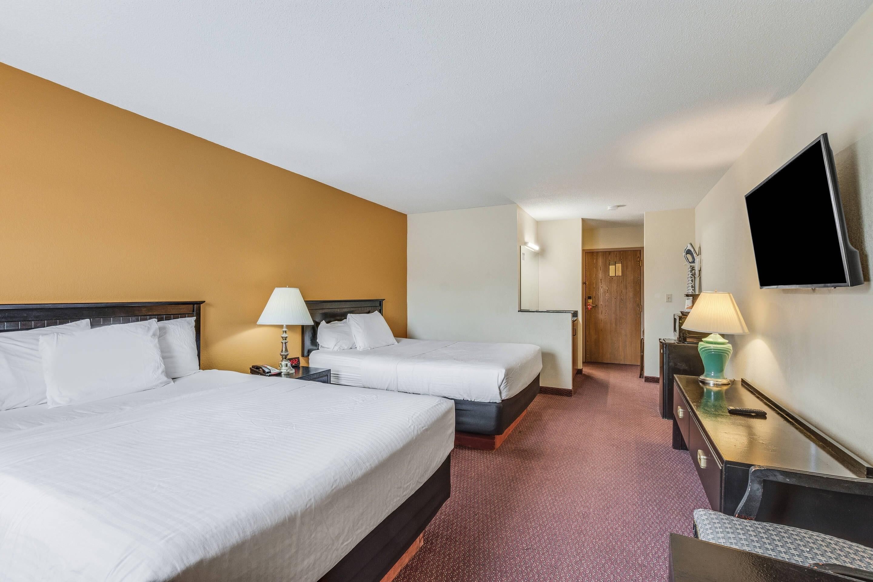 Habitación de hotel con dos camas, televisión, escritorio y lámpara.