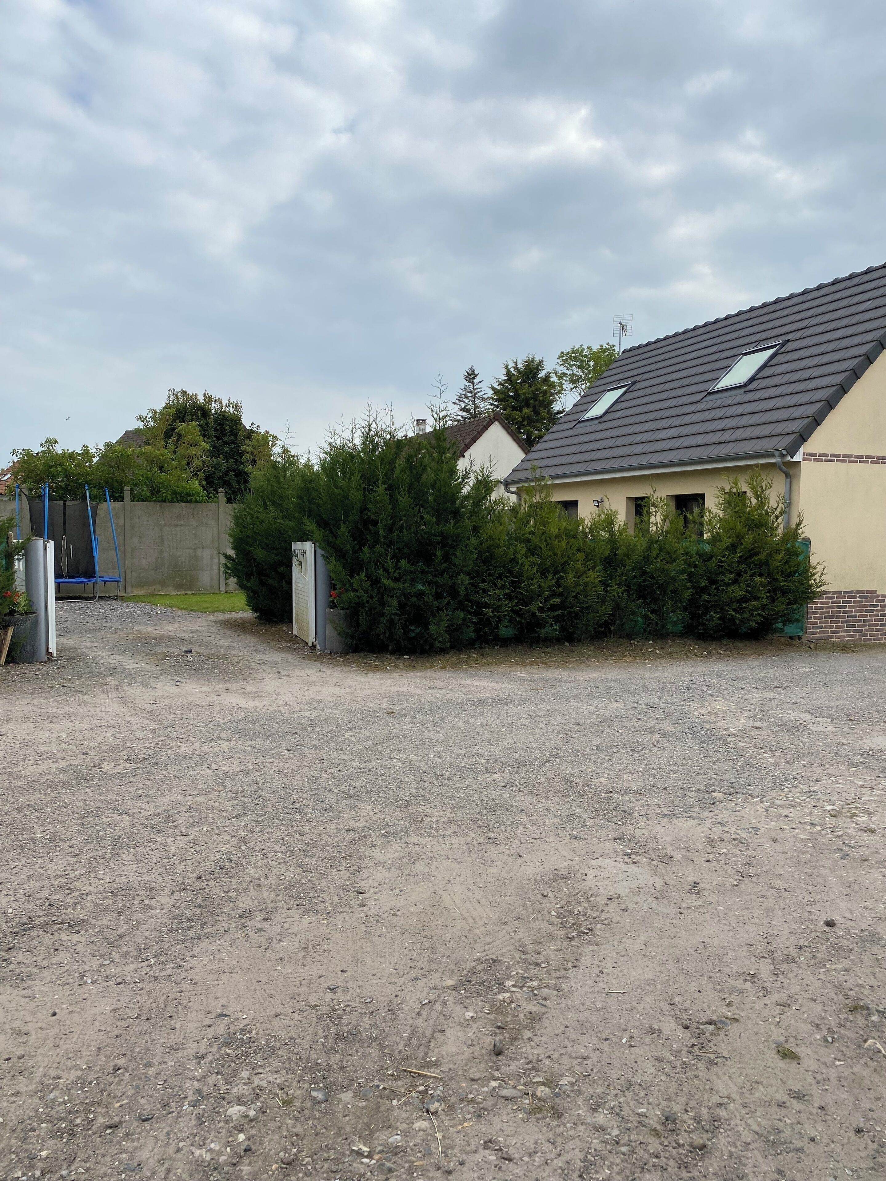 A gravel driveway leading to a house with a sloped roof and skylights.