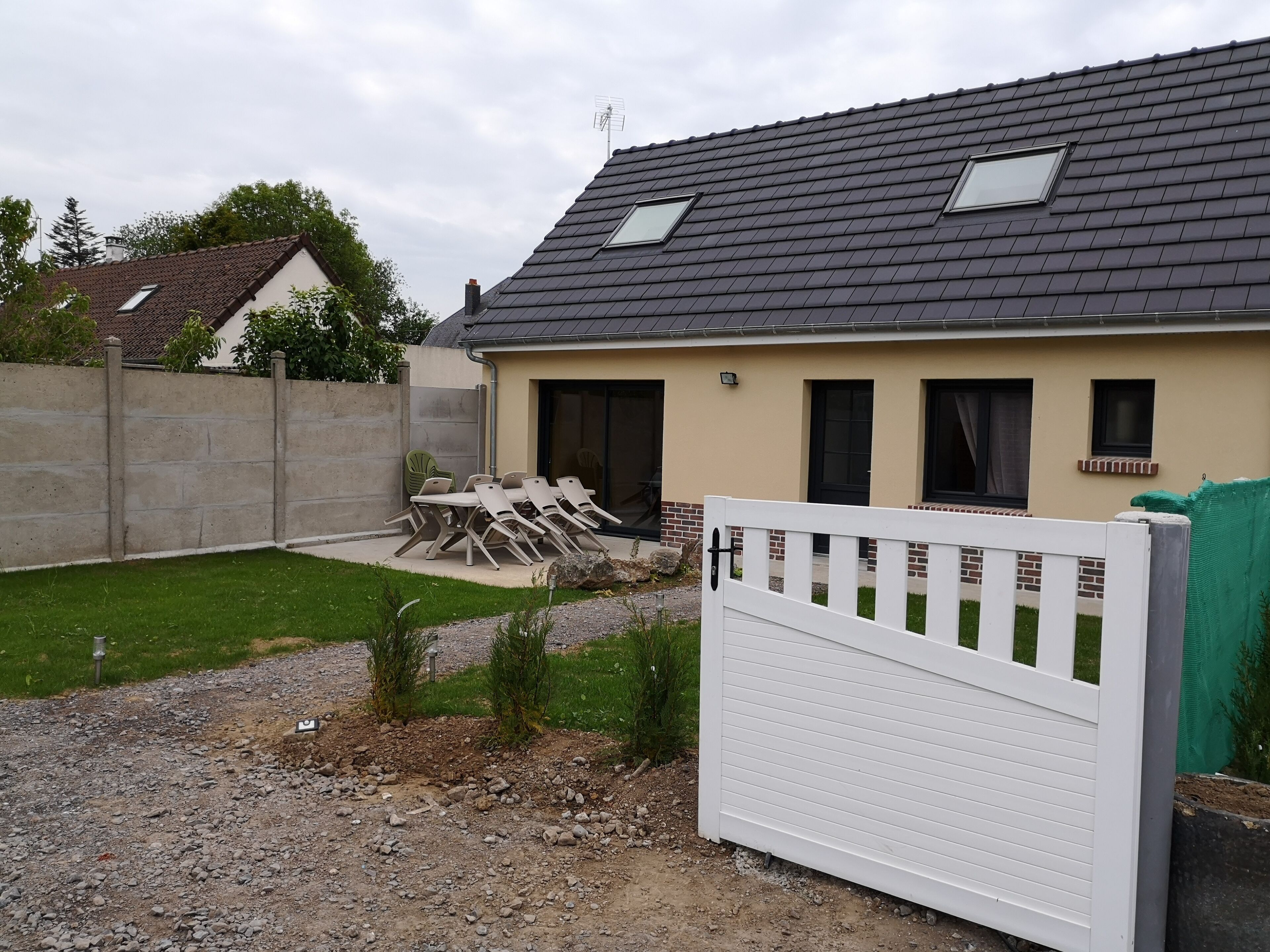 A house with a sloped roof, a fenced backyard, and a gated entrance.