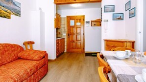 Un espacio habitable pequeño con sofá, mesa de comedor y armarios de madera.