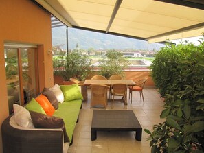 A covered patio with a sofa, table, chairs, and potted plants. - Relax Suite in Merano (Merano)